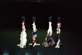 Stage design by Isabelle Lange for the performance Masterpiece. Four Speakers wrapped in fabrics in white, red, and blue, standing on a dark stage. the scene is dimly lit, adding an eerie ambiance. ISO LA - Isabelle Lange