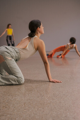 Three performers practicing dance in a spacious room during the performance Tirana. Luisa Alfonso in the foreground is in a crouching position while two others are further back. They are wearing costumes by Isabelle Lange. ISO LA - Isabelle Lange